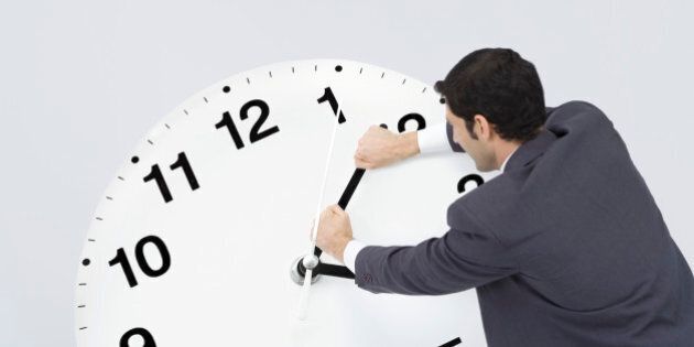 Businessman pushing back hands of clock