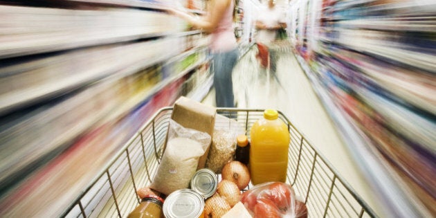 Shopping cart approaches woman in aisle. Motion blur.