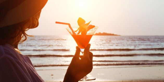 silhouette of woman with cocktail on the beach
