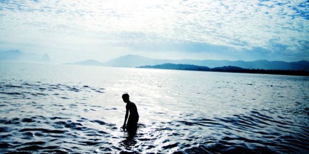 Silhouette of person wading in the sea
