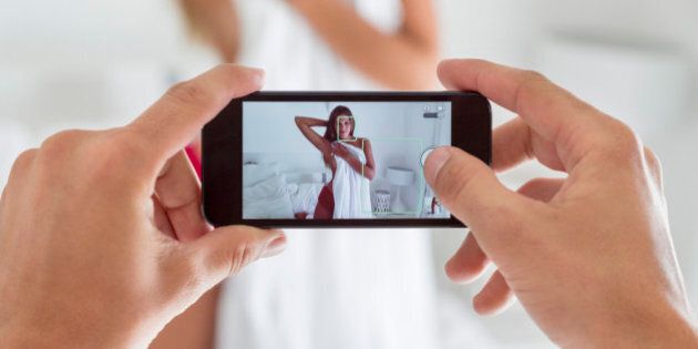 Man taking picture of his girlfriend in the bedroom