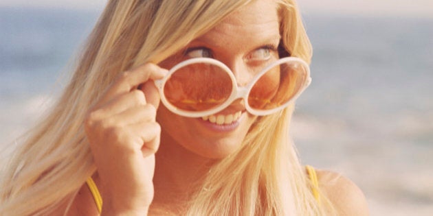 Woman with big sunglasses on beach, smiling