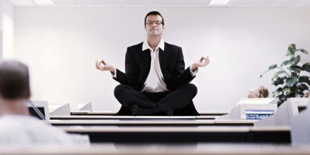 Businessman meditating on office desk