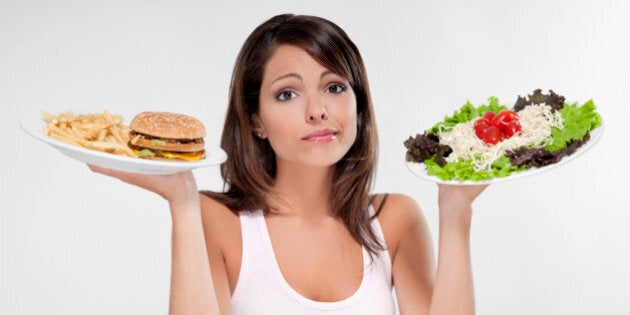 Woman choosing between a hamburger and salad