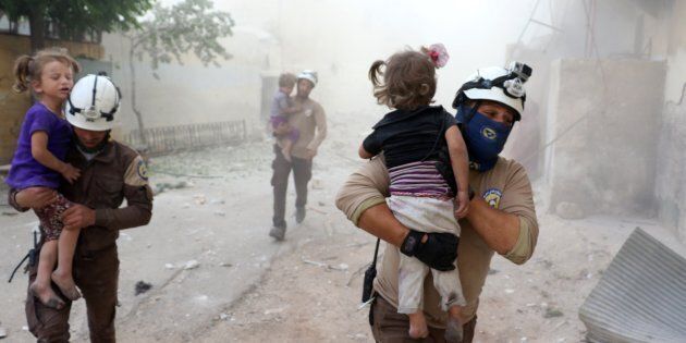 ALEPPO, SYRIA - MAY 31: A man carries a wounded kid after Assad forces' airstrike, hit residential areas in Tal Zarazir Neighborhoof of Sukkeri District of Aleppo, Syria on May 31, 2016. (Photo by Ibrahim Ebu Leys/Anadolu Agency/Getty Images)