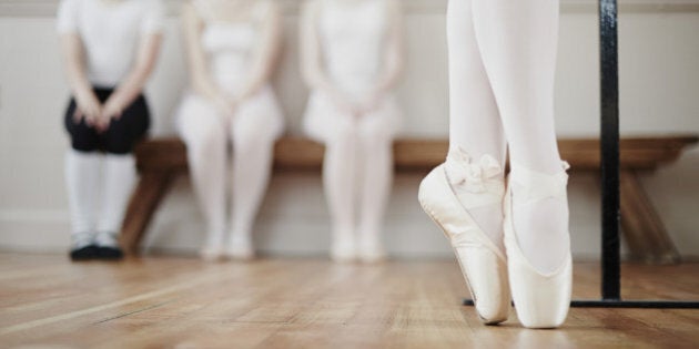 Female ballet dancer performing point work in front of peers in dance studio