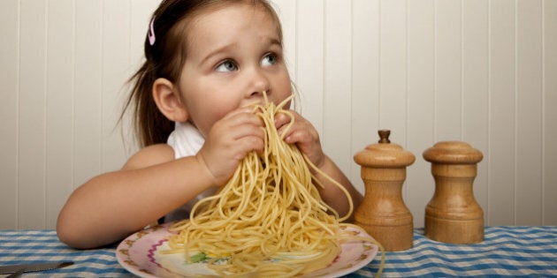 Little girl eating spaghetti with her hands