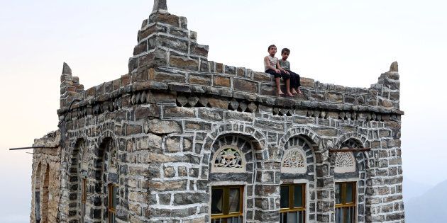 Young boys sit on the roof of their home in the mountains of Yemen's Jafariya district on May 31, 2016. Yemeni villagers have built an isolated community in the mountaintops, far beyond the conflict below.