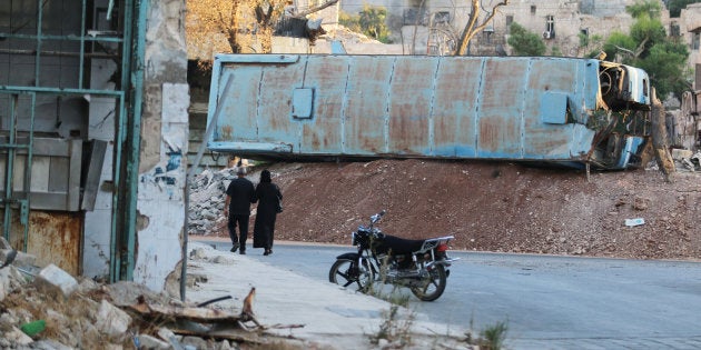 People pass damaged buses positioned as barricades in the rebel-held Bab al-Hadid neighbourhood of Aleppo, Syria, September 14, 2016. REUTERS/Abdalrhman Ismail