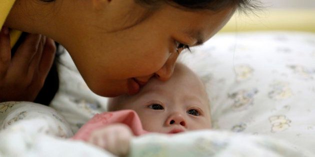 Gammy, a baby born with Down's Syndrome, is kissed by his surrogate mother Pattaramon Janbua at a hospital in Chonburi province August 3, 2014. According to Pattaramon, his Australian parents, through a local surrogate agency, asked her at her 7th month of pregnancy to terminate it because of his Down's Syndrome but she refused and kept the baby. The Australian parents instead took with them Gammy's twin sister who was born healthy. More than 3 million Thai baht ($93,360) was raised through an online campaign in Thailand in less than a day for the medical treatment of Gammy who suffers from potentially life threatening heart conditions and a serious lung infection, local media reported. REUTERS/Damir Sagolj (THAILAND - Tags: SOCIETY HEALTH)
