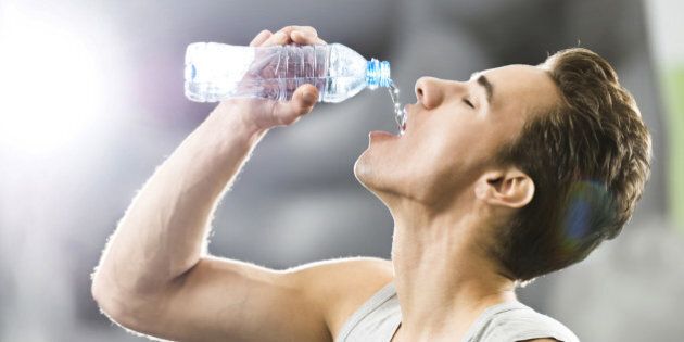 Thirsty young man drinking water after exercising.