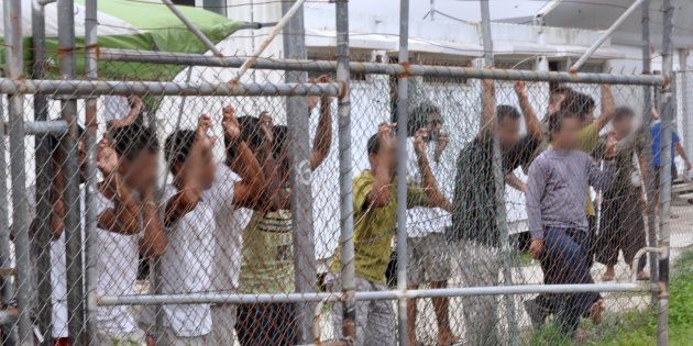 Asylum-seekers look through a fence at the Manus Island detention centre.