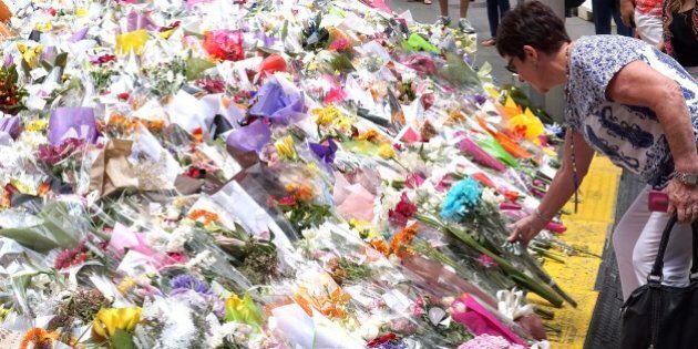 A woman places a floral tribute at a temporary memorial site close to the Lindt Chocolat Cafe in Sydney, Australia, Friday, Dec. 19, 2014. An Iranian-born, self-styled cleric with a lengthy criminal history, burst into a downtown Sydney cafe on Monday wielding a shotgun, taking 17 people hostage. The siege ended 16 hours later when police stormed into the cafe to free the captives, two of whom were killed in a barrage of gunfire, along with the gunman. (AP Photo/Rob Griffith)