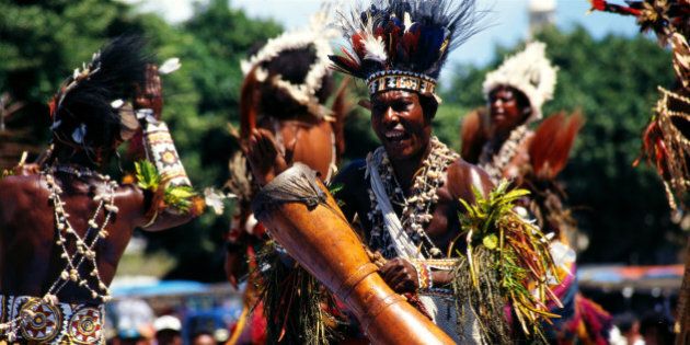 Papua New Guinea, men in traditional dress beating drum B1716