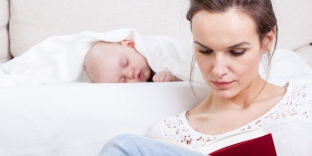Mother reading a book while baby's sleeping