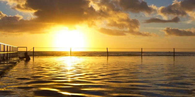 A lone swimmer enjoying a very early morning dip in the outdoor pools on Cronulla beach, NSW, Australia. This is not a HDR shot.