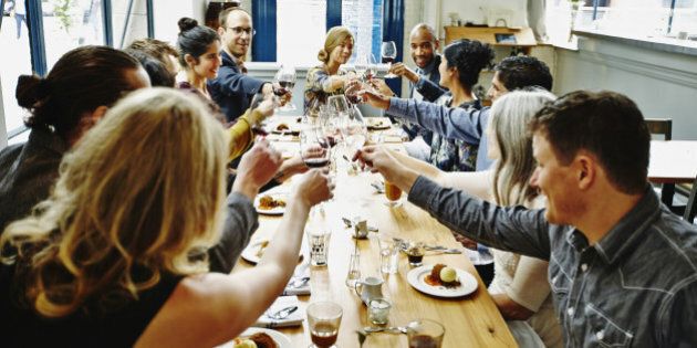 Smiling group of friends toasting at dinner party in restaurant