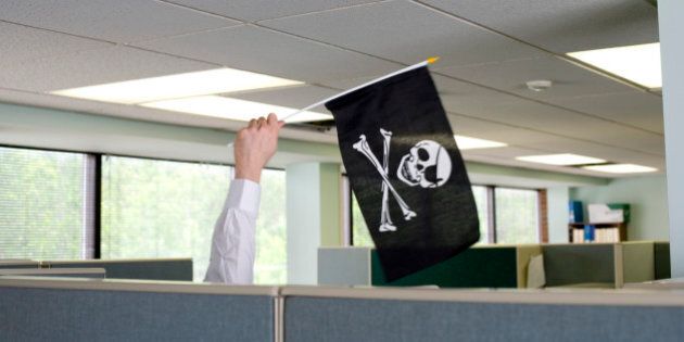 Businessman waving jolly roger flag cubicle wall