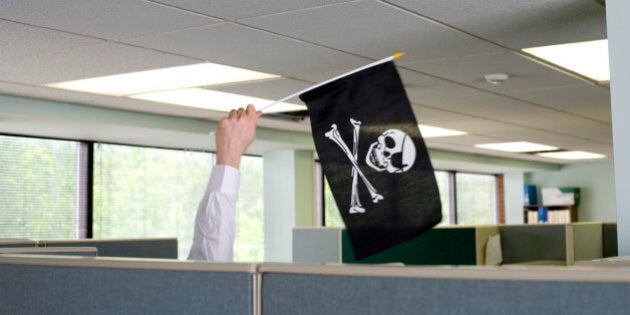 Businessman waving jolly roger flag cubicle wall