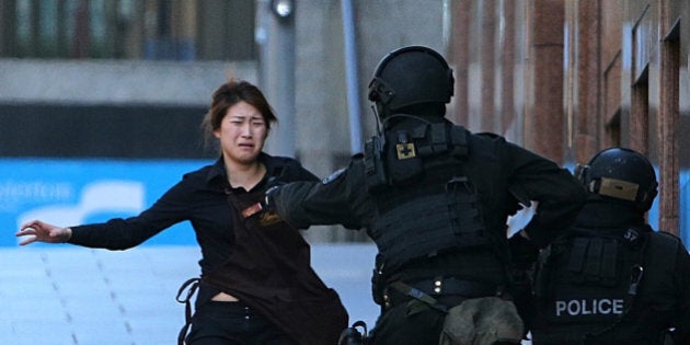 FILE - In this Dec. 15, 2014 file photo, Bae Jie-un, a staff member of a Sydney cafe and one of the hostages, runs to armed tactical response police officers for safety after she escaped from a cafe under siege in Sydney, Australia. Bae and her colleague told Seven Network television in paid interviews broadcast Sunday, Feb. 8, 2015, how Bae quietly unbolted an internal door to escape the cafe without gunman Man Horan Monis noticing.(AP Photo/Rob Griffith, File)