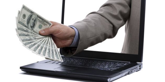 Holding one hundred dollar bills through a laptop screen concept for internet e-commerce, paying and electronic banking