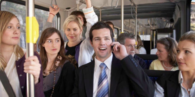 Businessman using mobile phone, laughing on bus