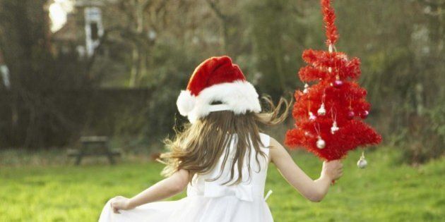 Girl dancing in field with Christmas tree