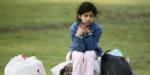 EDIRNE, TURKEY - SEPTEMBER 22: A refugee girl sitting on bags is seen at Edirne's Saraici square where the Syrian refugees camp while waiting for the borders to be opened on September 22, 2015 in Edirne, Turkey. Thousands of refugees continue to flock to Edirne, which borders Greece and Bulgaria, in an attempt to cross further into Europe. (Photo by Berk Ozkan/Anadolu Agency/Getty Images)