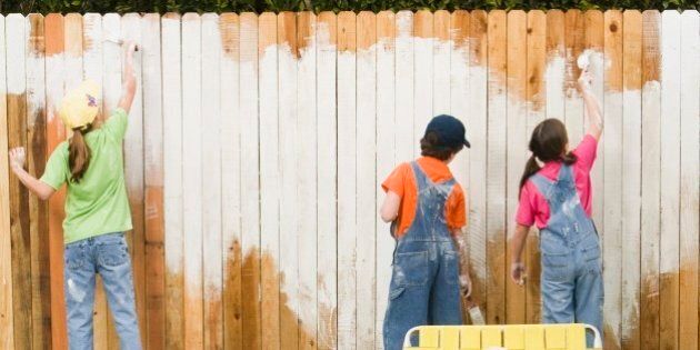 Mixed Race family painting fence
