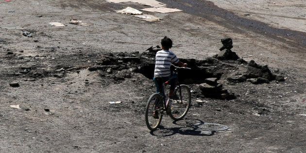 A boy rides a bicycle near a hole in the ground after an airstrike on Sunday in the rebel-held town of Dael, in Deraa Governorate, Syria September 19, 2016.