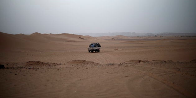 A vehicle transporting a group of African migrants drives through the desert on their journey from Ghat in southwest Libya May 29, 2014. A smuggler was transporting a group of African migrants through the desert to northern Libya. Libya's southwestern tip in the Sahara bordering Algeria and Niger has turned into an open door for illegal migrants from sub-Saharan countries heading for Europe, with the chaotic government in Tripoli appearing to have abandoned all control. The revolt that overthrew Libyan leader Muammar Gaddafi three years ago emptied Libya's arsenals, flooded the region with guns and dismantled much of the state apparatus, giving well-organised smuggler networks the run of the border. Border officials say up to 200 Africans cross the Ghat border strip every day, most headed north to the Mediterranean coast for the onward trip to Europe by boat. Picture taken May 29, 2014. REUTERS/Ahmed Jadallah (LIBYA - Tags: SOCIETY POLITICS IMMIGRATION)ATTENTION EDITORS: PICTURE 17 OF 31 FOR PACKAGE 'MIGRANT FLIGHT THROUGH LIBYA'TO FIND ALL IMAGES SEARCH 'JADALLAH GHAT'