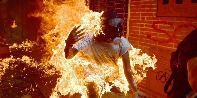 TOPSHOT - A demonstrator catches fire during clashes with riot police within a protest against Venezuelan President Nicolas Maduro, in Caracas on May 3, 2017.Venezuela's angry opposition rallied Wednesday vowing huge street protests against President Nicolas Maduro's plan to rewrite the constitution and accusing him of dodging elections to cling to power despite deadly unrest. / AFP PHOTO / RONALDO SCHEMIDT (Photo credit should read RONALDO SCHEMIDT/AFP/Getty Images)