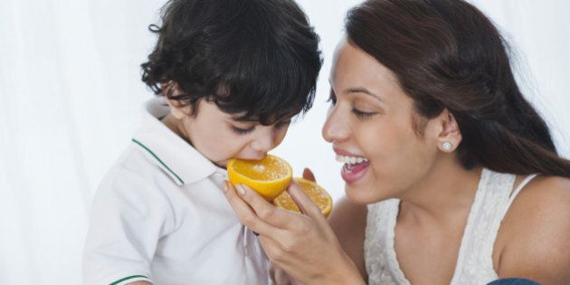 Woman feeding orange to her son