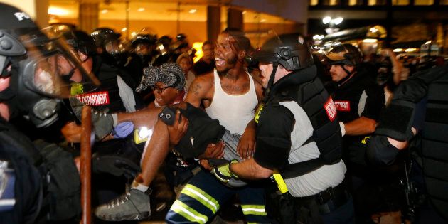 CHARLOTTE, NC - SEPTEMBER 21: Police and protesters carry a seriously wounded protester into the parking area of the the Omni Hotel during a march to protest the death of Keith Scott September 21, 2016 in Carolina. Scott, who was black, was shot and killed at an apartment complex near UNC Charlotte by police officers, who say they warned Scott to drop a gun he was allegedly holding. (Photo by Brian Blanco/Getty Images)