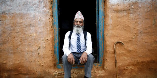 Durga Kami, 68, who is studying tenth grade at Shree Kala Bhairab Higher Secondary School, poses for a picture wearing his school uniform at the door of his one-room house in Syangja, Nepal, June 5, 2016. REUTERS/Navesh Chitrakar. SEARCH