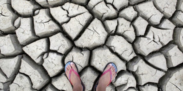 Large cracks in rock hard earth of water hole during dry season drought.