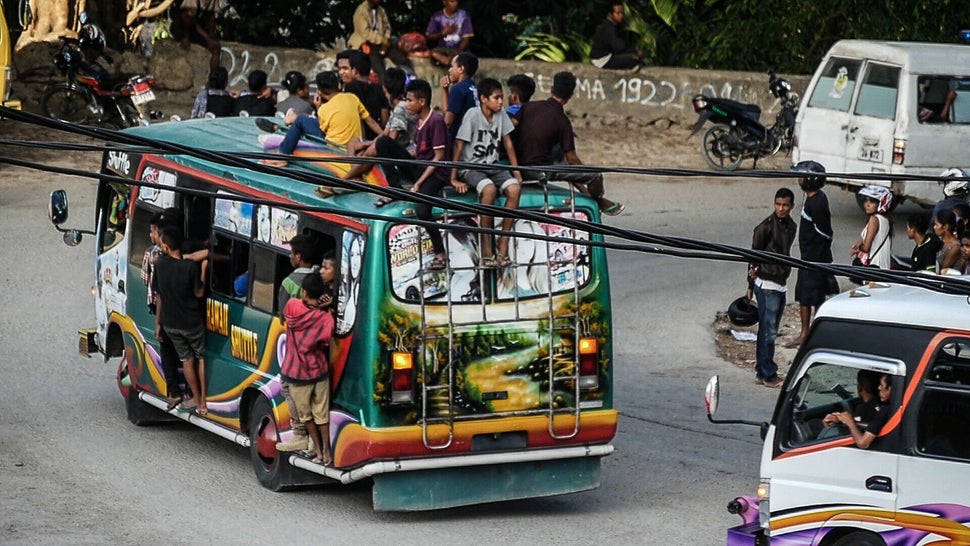 Buses and trucks spill at the sides with passengers. Just your standard form of Transport in Timor. Baucau, Timor-Leste.