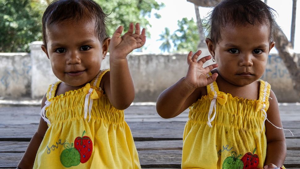 These gorgeous girls look like a mirror image as they wave 'hi' to the camera. Baucau, Timor-Leste.