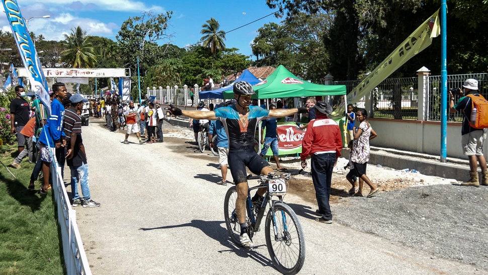 A relieved and spent rider comes through the finish line at Tour de Timor 2016. It's 5 days of rough terrain in hot, tropical climate. Baucau, Timor-Leste.