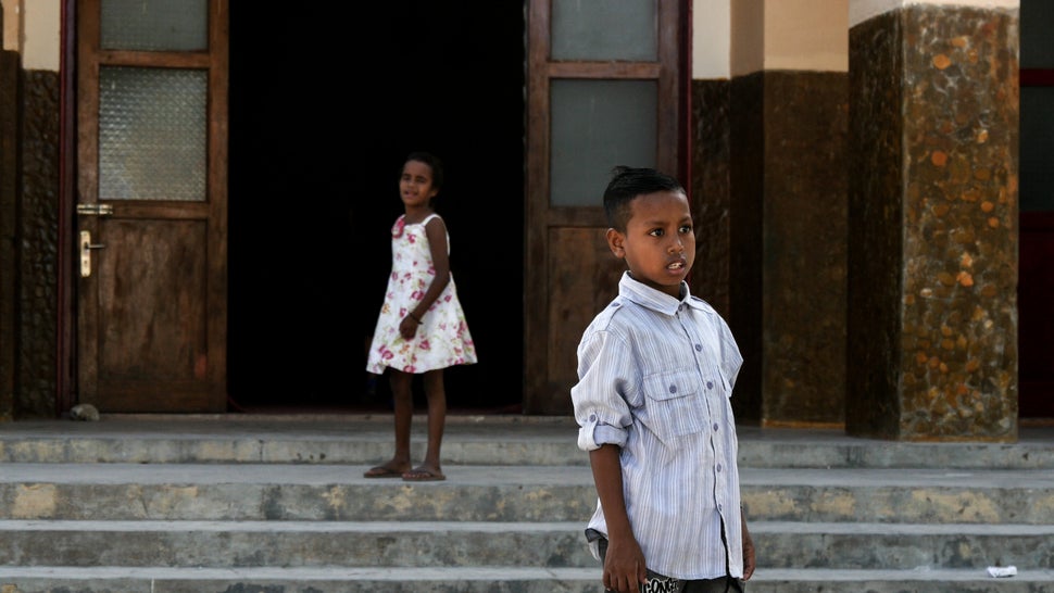 This boy is transfixed on the finish line as his sister calls him into church. Baucau, Timor-Leste.