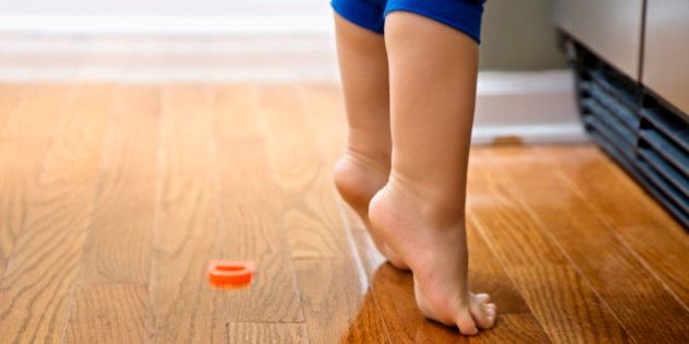 Feet of Caucasian toddler boy with magnets in front of refrigerator.