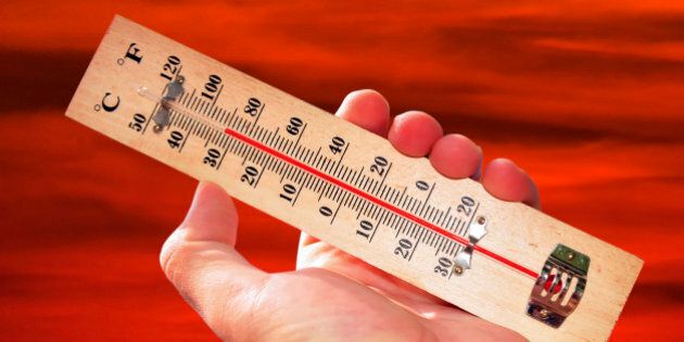 A hand and temperature scale over a red sky shows high temperatures during a heat wave.