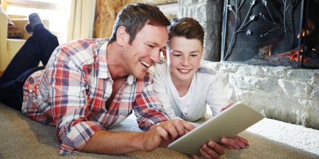 Father and son playing with digital tablet together