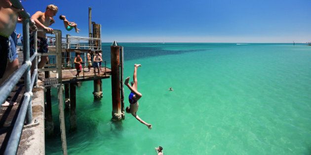 ADELAIDE, AUSTRALIA - JANUARY 13: A teengager jumps off the Glenelg jetty during a heat wave at Glenelg Beach on January 13, 2014 in Adelaide, Australia. Temperatures are expected to be over 40 degrees celsius all week with health authorities warning the young and elderly to remain indoors. (Photo by Daniel Kalisz/Getty Images)