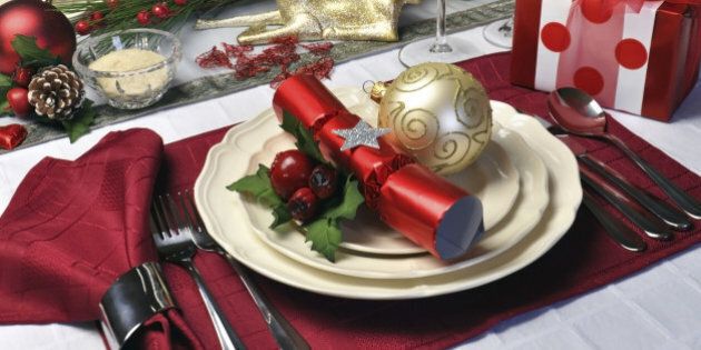 Modern and stylish Christmas dinner table setting including plates, glasses and placemats, bon bons and Christmas decorations Landscape (horizontal) composition.