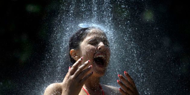 A girl takes a cold shower in order to refresh herself at Ada Ciganlija lake in Belgrade, Serbia, Thursday, June 20, 2013. The Balkan region is experiencing a heat wave, with temperatures rising as high as 37 degrees Celsius (99 Fahrenheit). (AP Photo/ Marko Drobnjakovic)