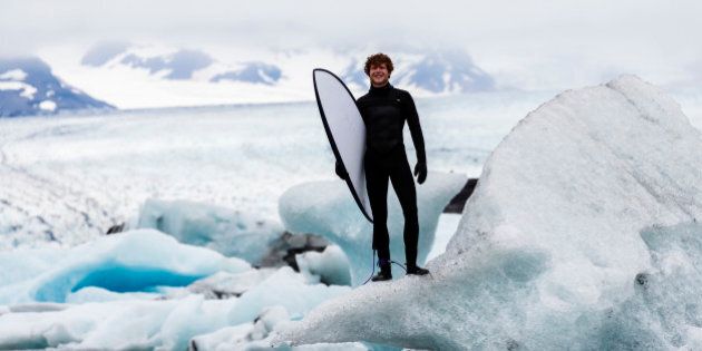 Caucasian surfer carrying board near glacial water