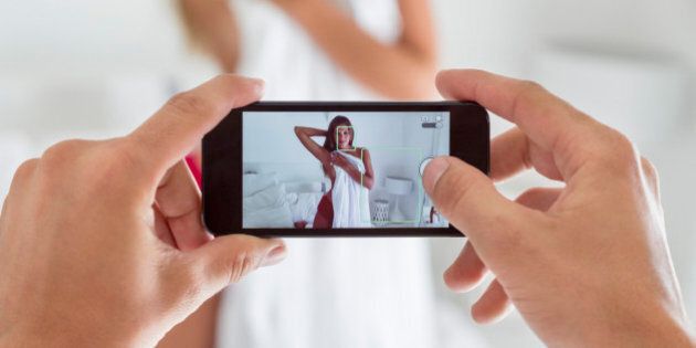 Man taking picture of his girlfriend in the bedroom