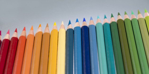 Colouring pencils in a row on a grey background.