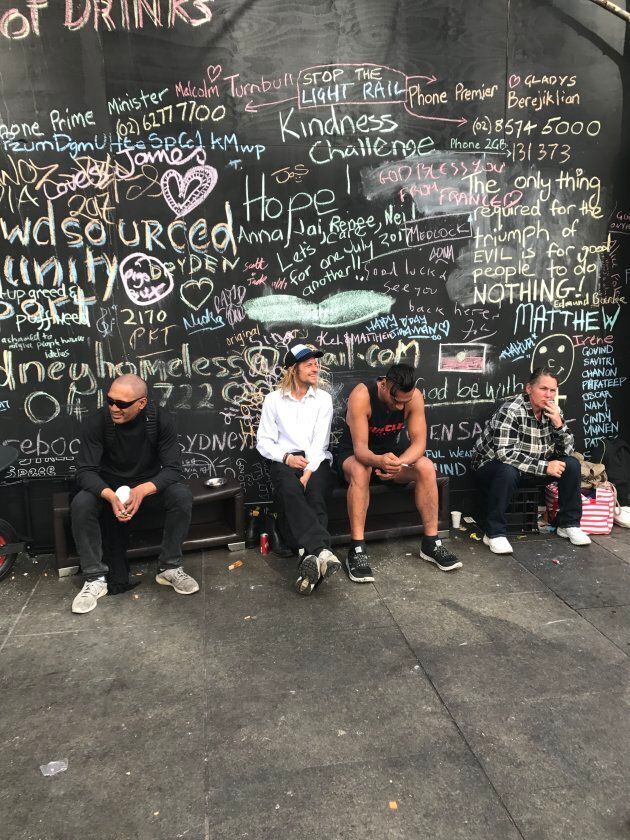 A group of men take in the day under a wall opposite the tent settlement on Martin Place. The six month old settlement is breaking up after consultation with police.